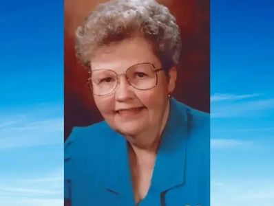 Portrait of an elderly woman with glasses and curly hair.