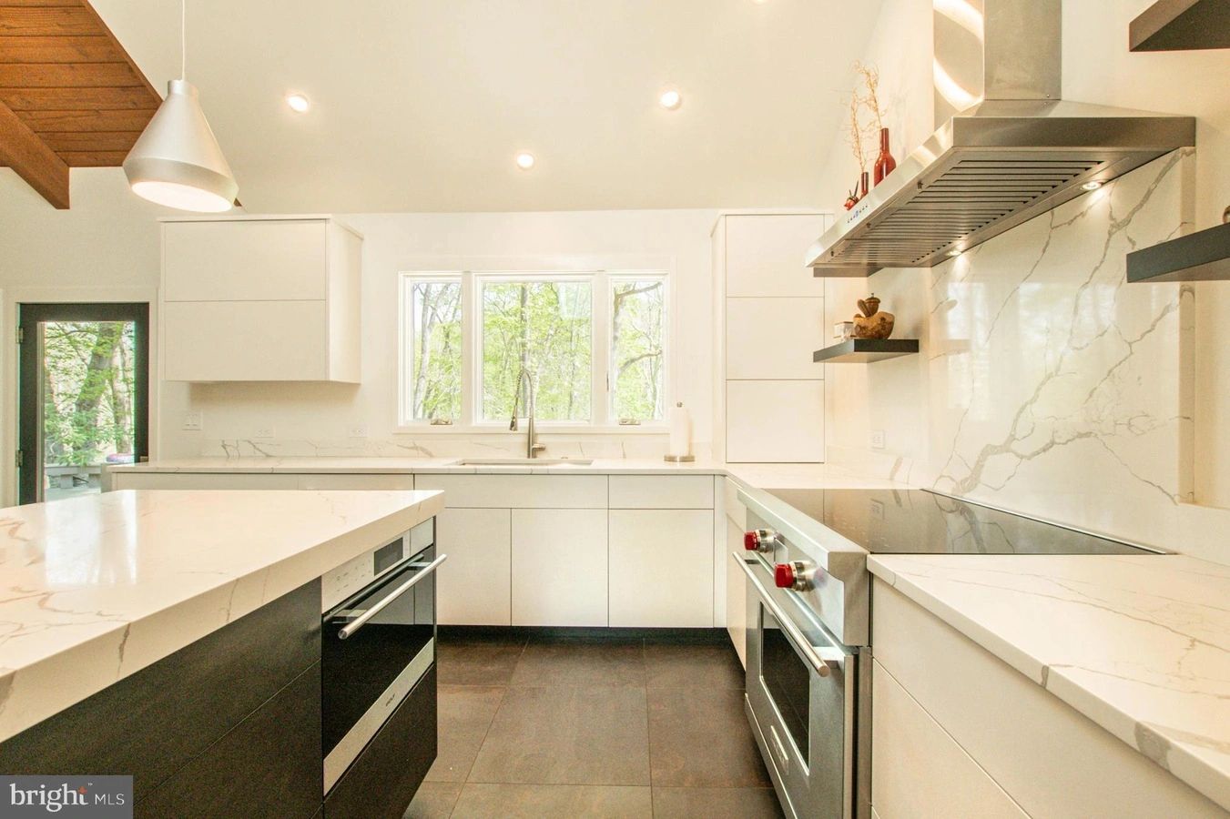 Modern kitchen with white marble countertops and stainless steel appliances.
