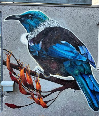 Vibrant mural of a blue bird perched on a branch with orange flowers.