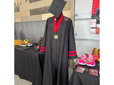 Graduation gown, cap, and pink sneakers on display.