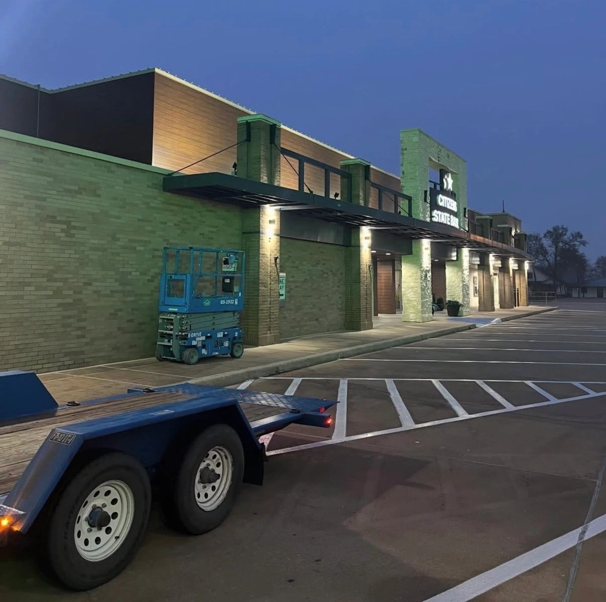 Evening view of a quiet parking lot outside Citizens State Bank with a blue lift and trailer.