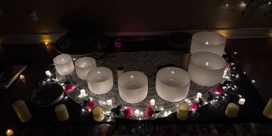 A serene arrangement of lit candles and crystal singing bowls in a dim room.