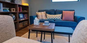 Cozy living room with blue sofa and wooden shelves under warm lighting.