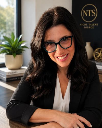 Woman with glasses smiling at her desk.