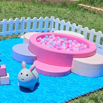 Colorful kids' play area with a ball pit and bunny toy outdoors.
