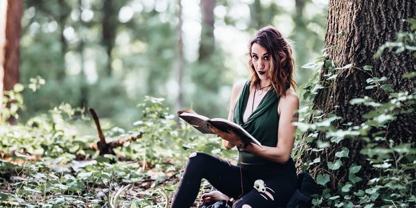 Samantha Boyd sitting in a forest with her leatherbound journal