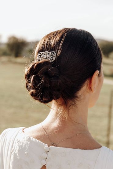 Peinado elegante con broche decorativo y vestido blanco.