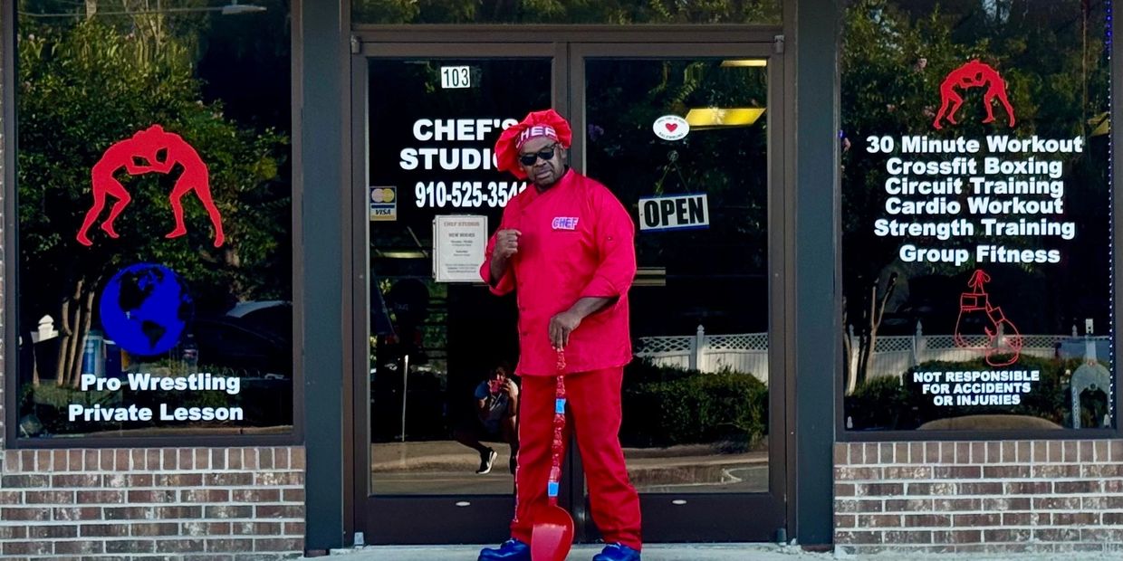 Chef in red outfit standing outside Chef's Studio with workout and wrestling lessons.