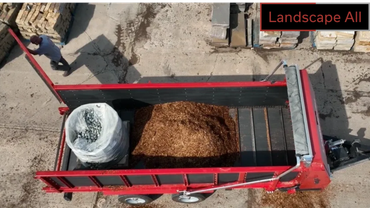 Top-down view of a red trailer loaded with mulch and a bag of materials.
