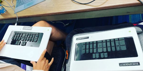 An image of two LightSpeed Steno machines in two stenographers' laps at a desk. 