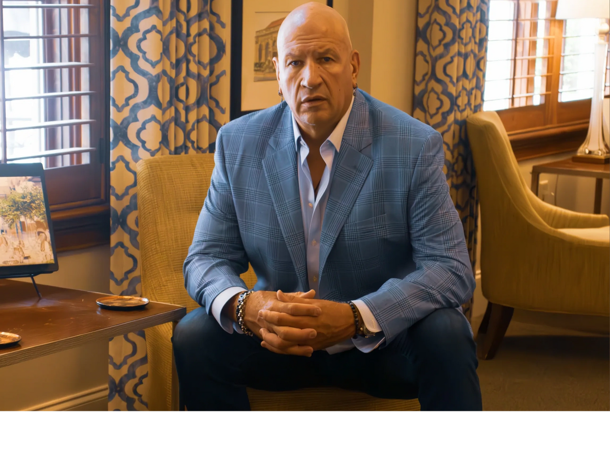 Man in a blue checkered blazer sitting in a cozy room.