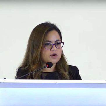 Mujer con gafas hablando en un podio.