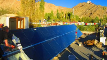 Person working on solar panels in a mountainous area.