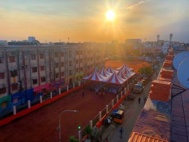 Sunset over a city street with tents and parked vehicles.