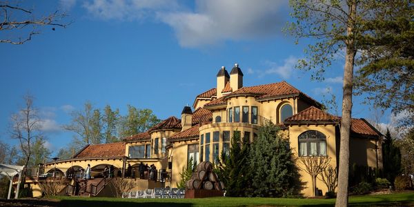 A large, elegant villa with terracotta roof tiles under a blue sky.