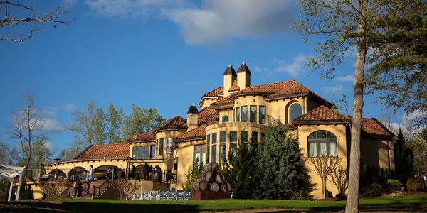 A large, elegant villa with terracotta roof tiles under a blue sky.