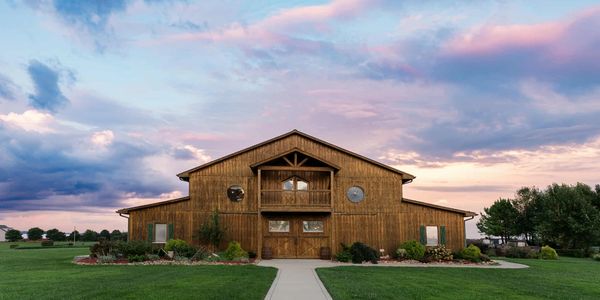 Rustic wooden barn under a colorful sky at sunset.