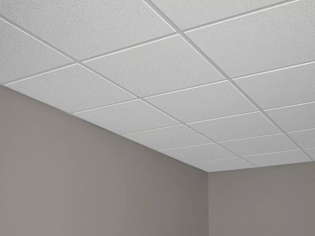 Drop ceiling with white tiles in a room corner.