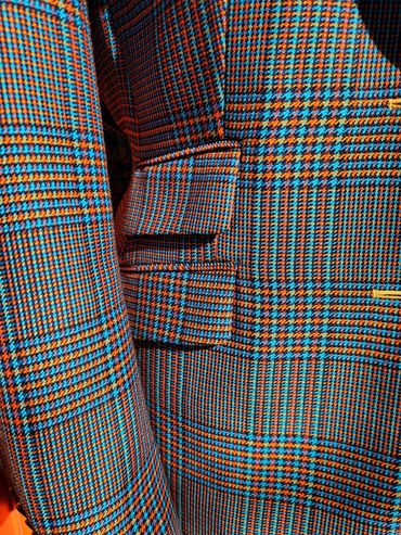 Custom orange and blue houndstooth suit with layered flap pockets and bold bespoke tailoring flair.