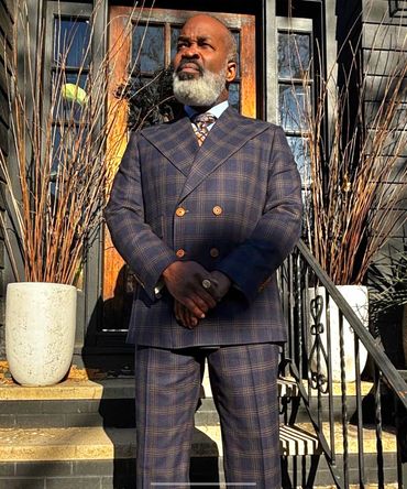 Impeccably tailored double-breasted suit with sharp lines, bold checks, and commanding poise.