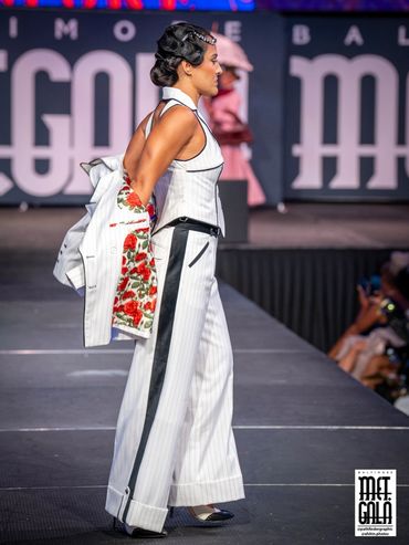 Model walking on a runway in a stylish white outfit.