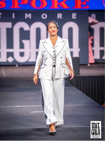 Model walking on runway in white pinstripe suit.