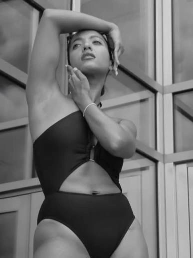 Woman posing confidently in a stylish black swimsuit.