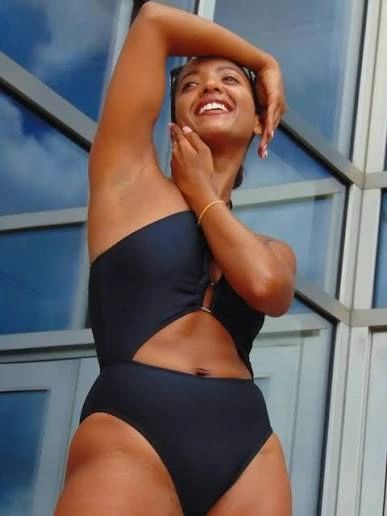 Woman in stylish black swimsuit posing confidently.