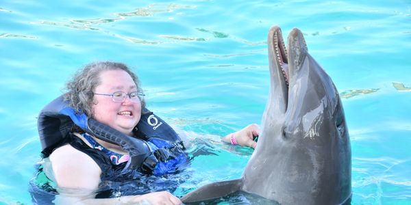 Woman swimming with a dolphin in clear water.