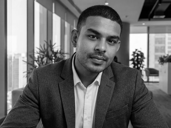 Young man in a suit looking confidently at the camera indoors.