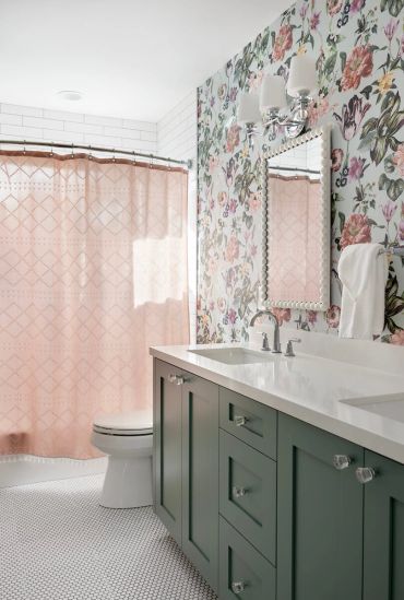 Bright bathroom with floral wallpaper and green cabinets.