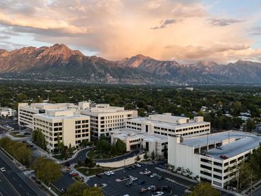 Modern buildings with mountain backdrop at sunset.