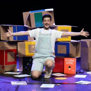 Man kneeling in front of colorful boxes with arms wide open.