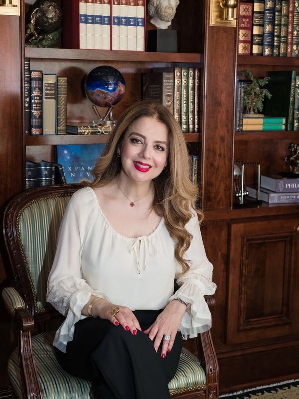 Woman in white blouse sitting in a classic wooden chair in a home library.