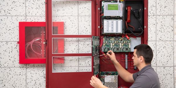 Fire alarm technician servicing a fire alarm panel.