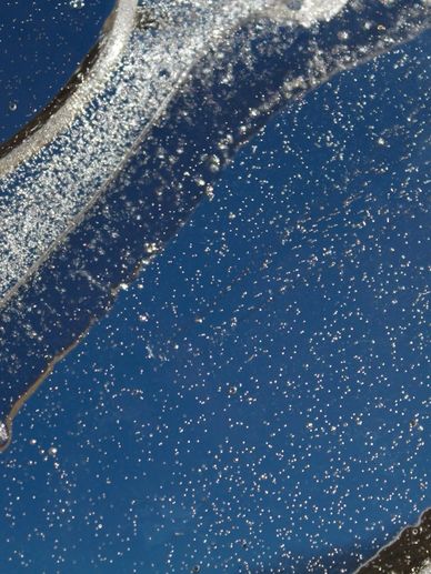 Close-up of ice with bubbles against a deep blue sky.