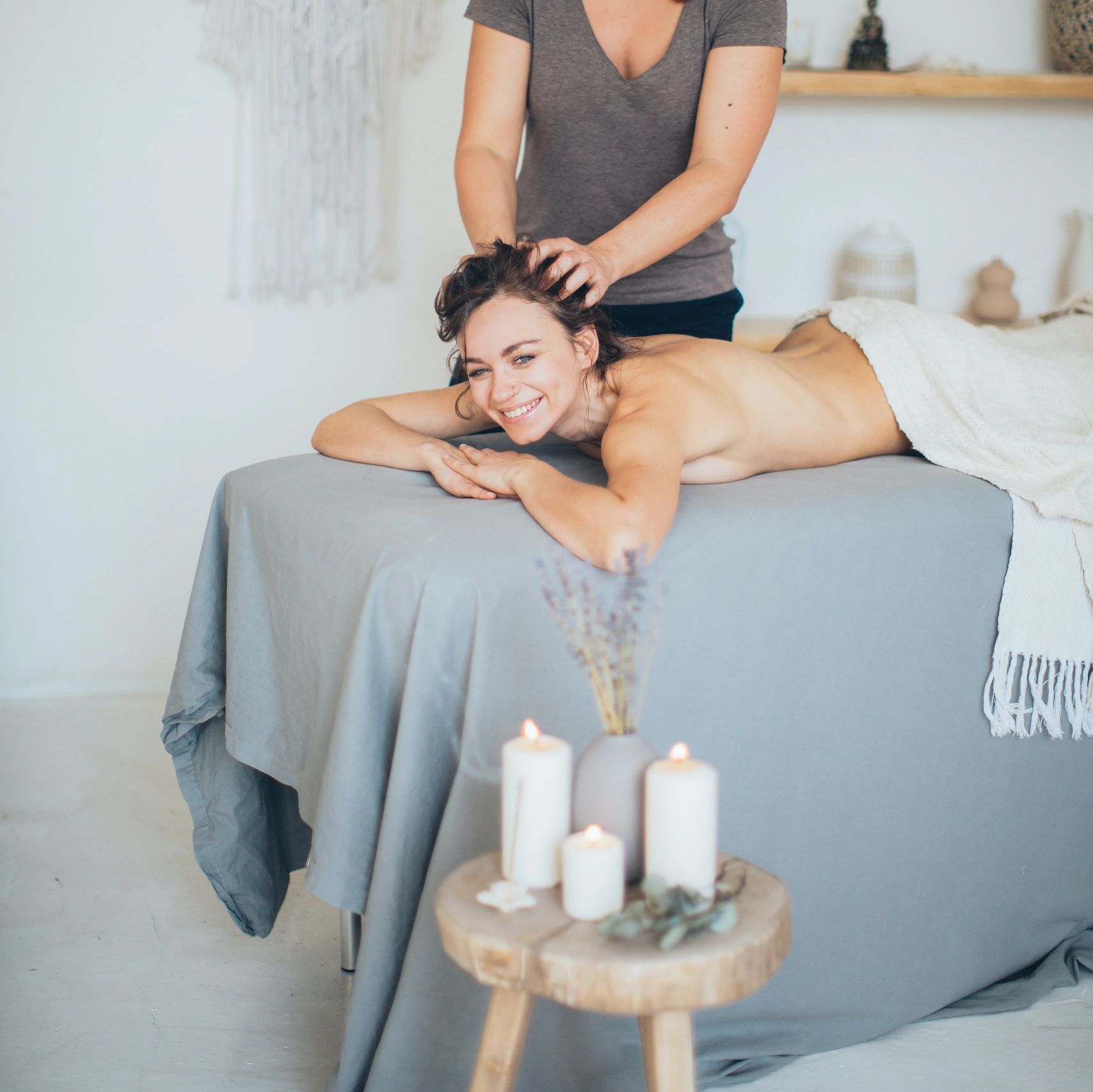 Massage Therapist performing a head massage on a massage table next to a table with candles.