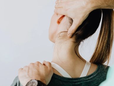 Massage therapist stretching a woman's neck by pushing on her head and shoulder. 