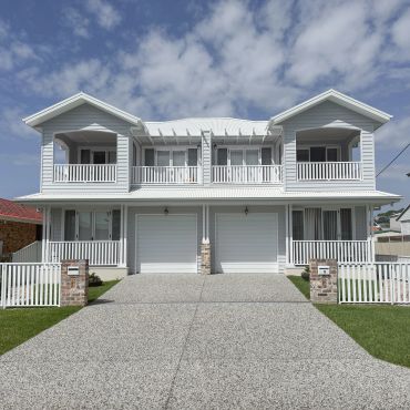 Modern duplex house with symmetrical design and white picket fences.