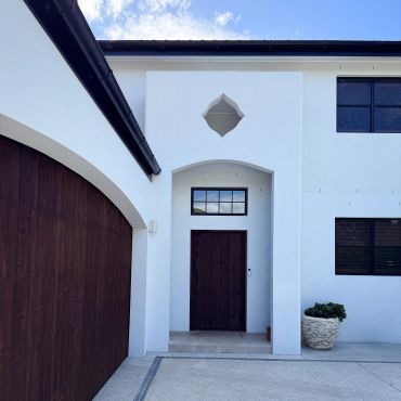 Modern white house entrance with wooden door and garage.