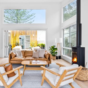 Cozy modern living room with leather sofa, wooden chairs, and fireplace.