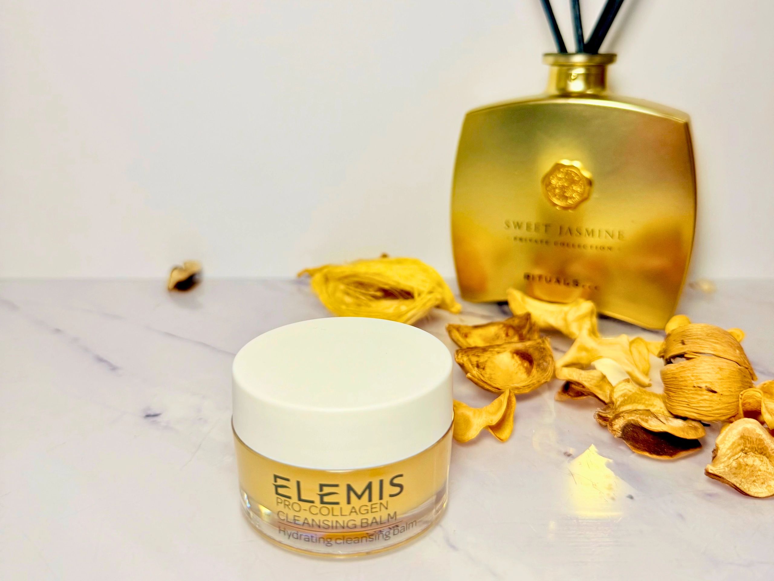 Elemis cleansing balm on a surface with gold diffuser and autumn theme 