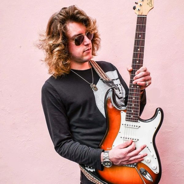 Man with sunglasses playing electric guitar.