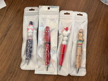 Four character-themed pens in packaging on a wooden surface.