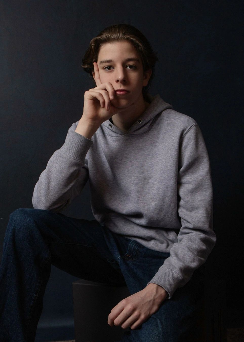 Confident young man with connected gaze in a gray hoodie and jeans.