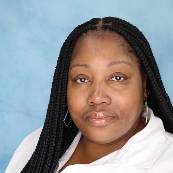 Close-up portrait of a woman with long braided hair against a blue background.