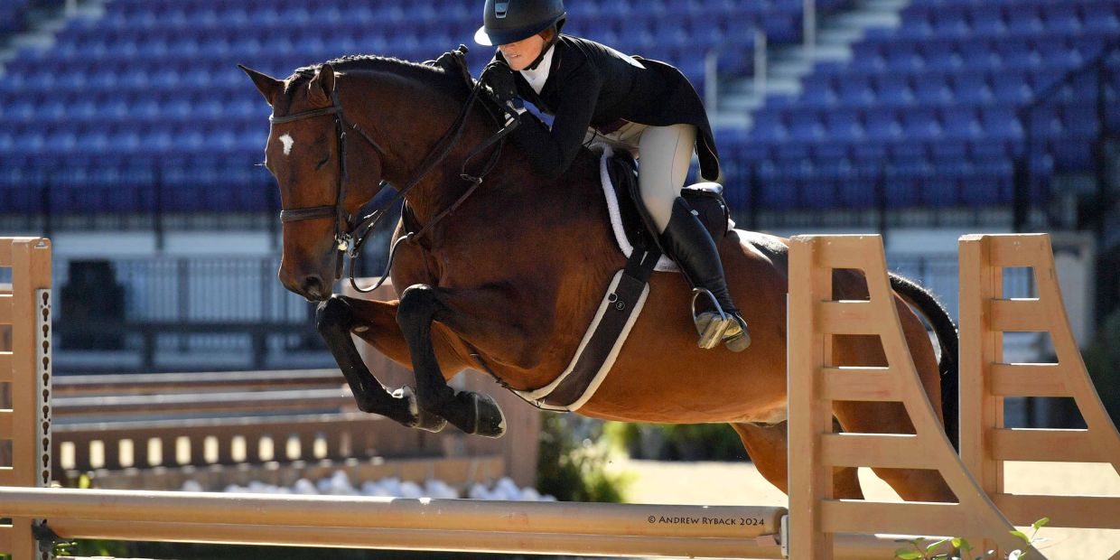 A rider and horse gracefully jump over an obstacle in an equestrian event.