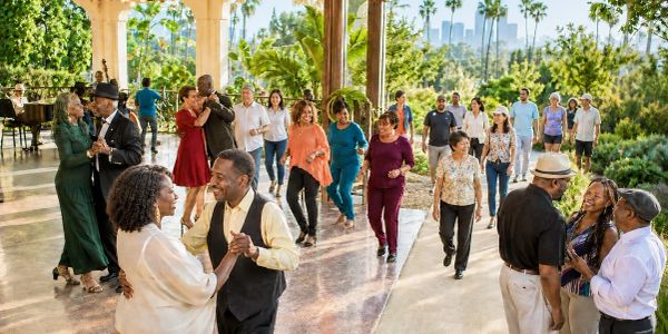 Diverse group dancing outdoors in a sunny garden.