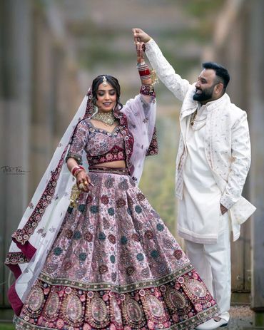 Bride and groom dancing in traditional Indian wedding attire.