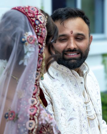 Groom smiling at bride in traditional attire during a wedding.